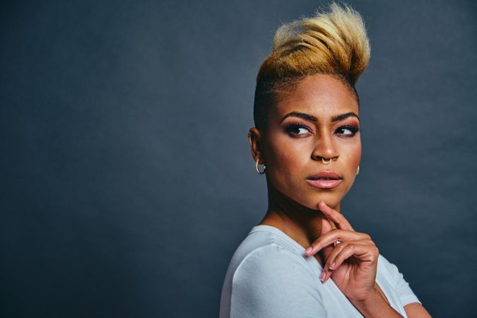 Portrait of proud Black woman with short blonde hair with hand to her chin looking away