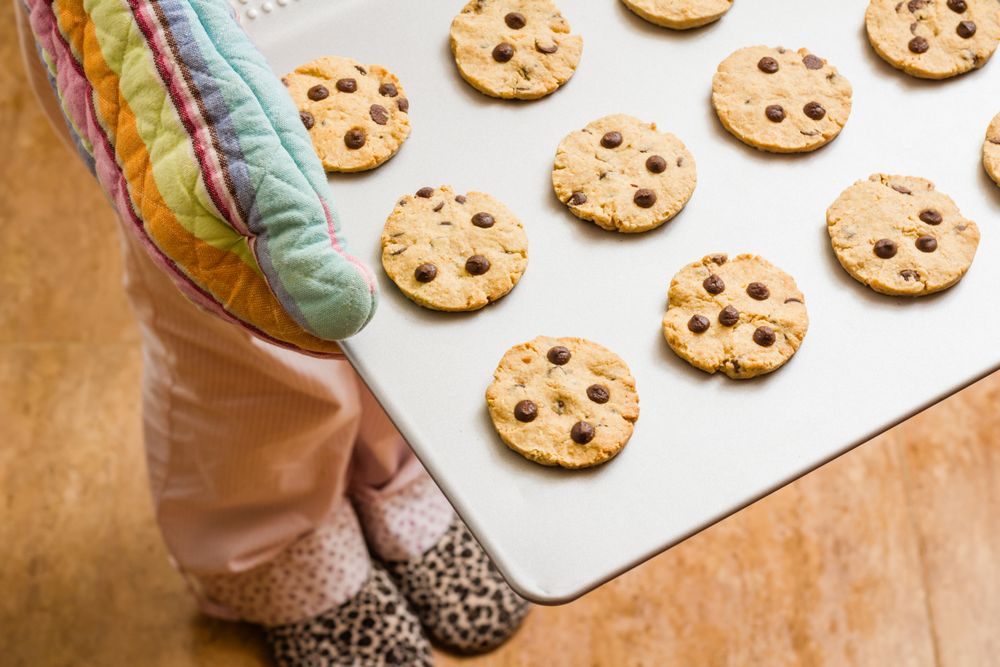 Woman holding a tray with baked cookies with kitchen gloves