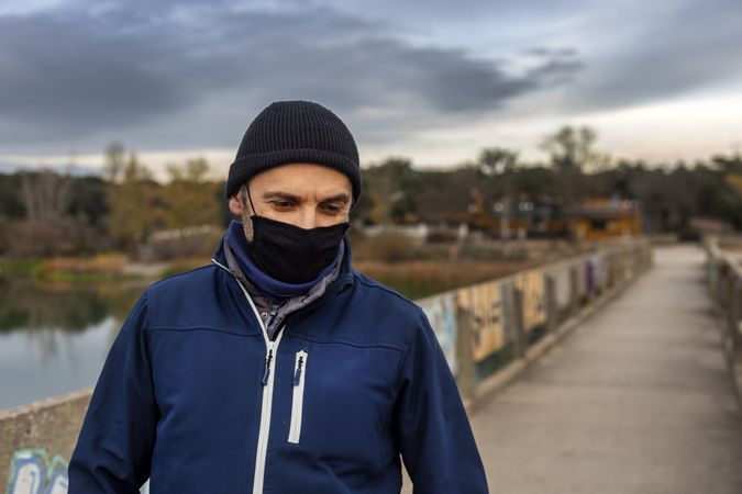 Man in dark knit cap and blue zip up hoodie standing on road