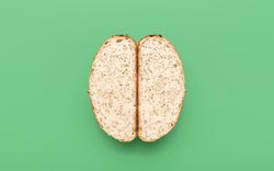 Bread with sesame seeds sliced in two, above view on a green background