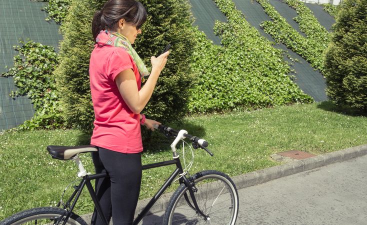 Sportive woman with fixie bike looking smartphone