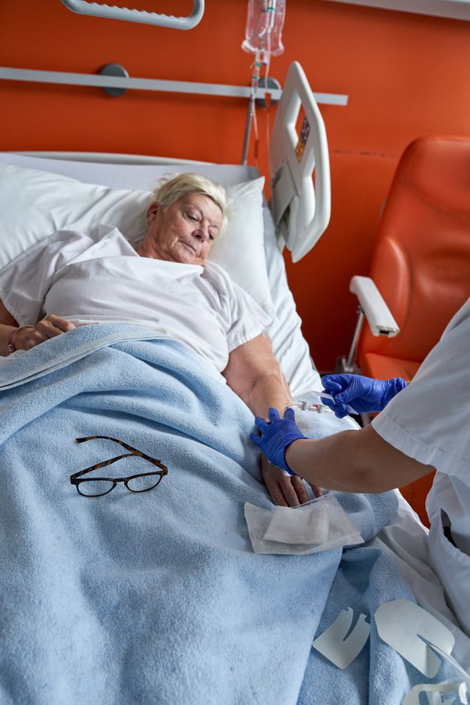Unrecognizable nurse doing intravenous injection to aged female