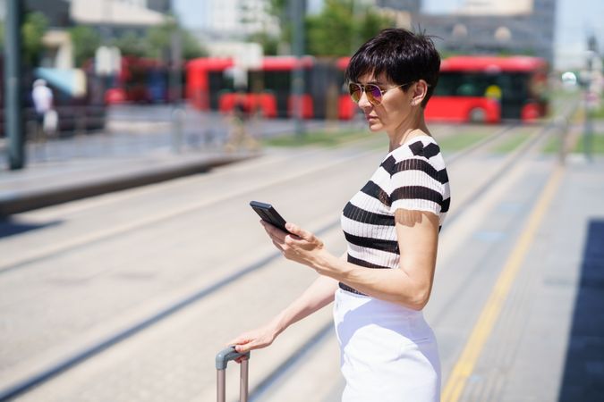 Woman checking phone while waiting for train