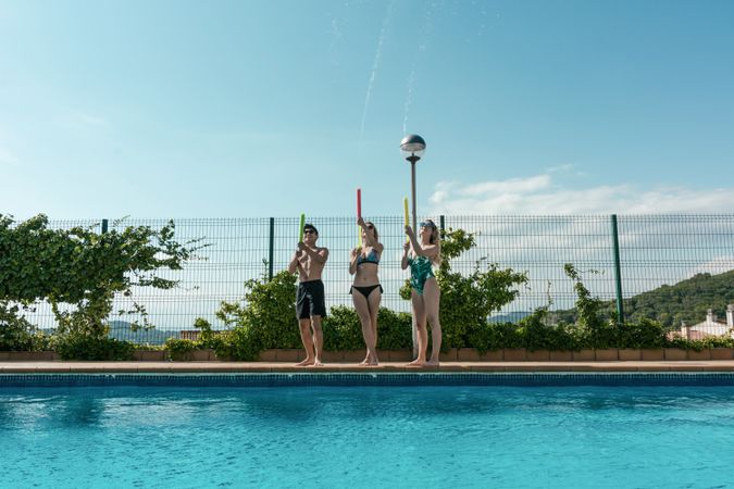 Friends playing with water pistols in the pool