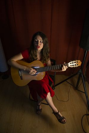 Woman singing and playing guitar on stage in lamplight