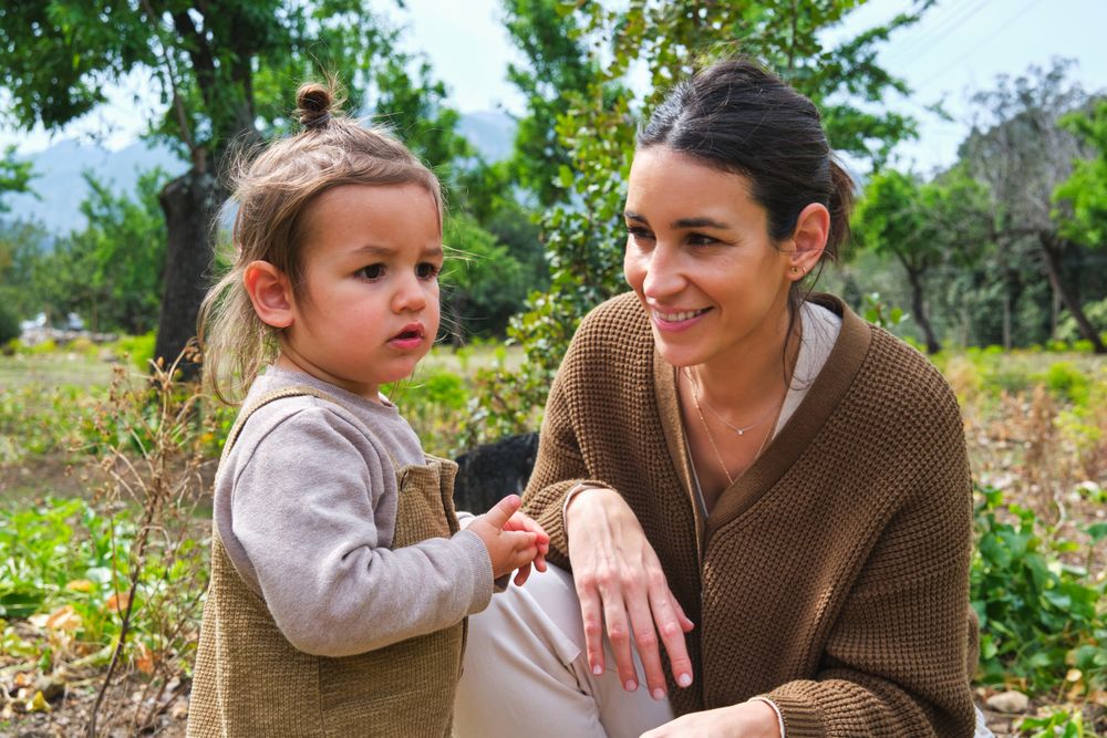 Smiling mother and cute daughter spending time in verdant park