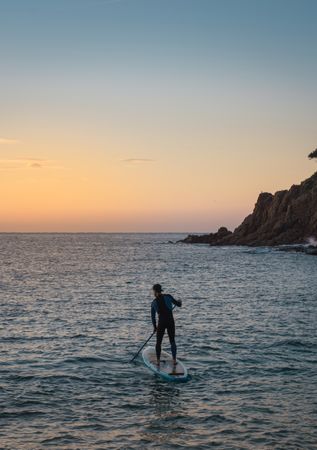 Man practicing paddle surfing with neoprene in a sunrise