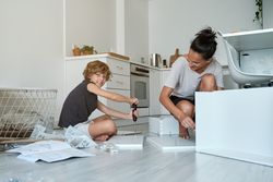Happy mother and son assembling new furniture in kitchen