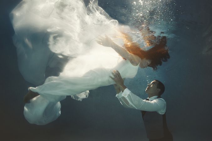 Bride and groom swimming underwater