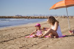 mother putting sun cream on toddler girl