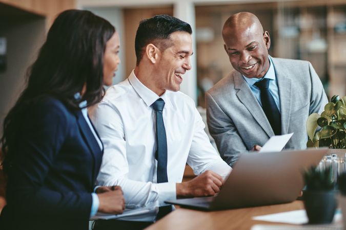 Group of people smiling around a laptop at an office