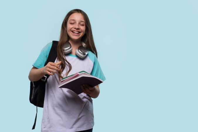 Girl with headphones around neck, holding notebook