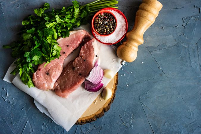 Top view of two raw pork chops with onion, garlic and herbs on counter with copy space