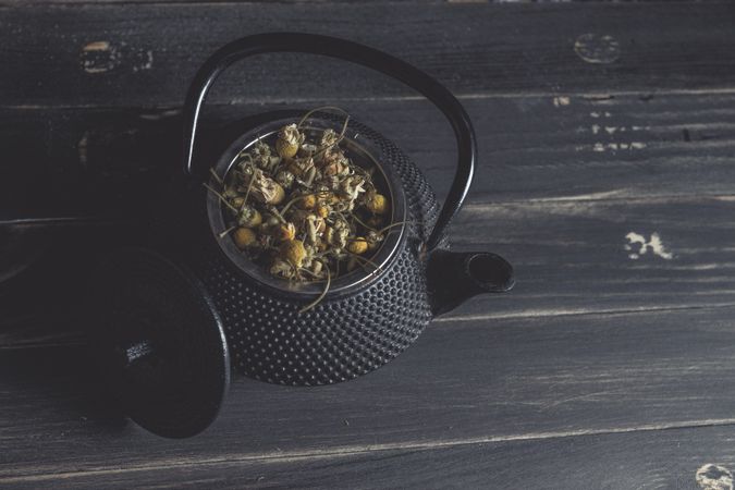 Spoonful of dried chamomile on brass teapot