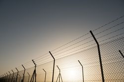 Bright sun behind security fence