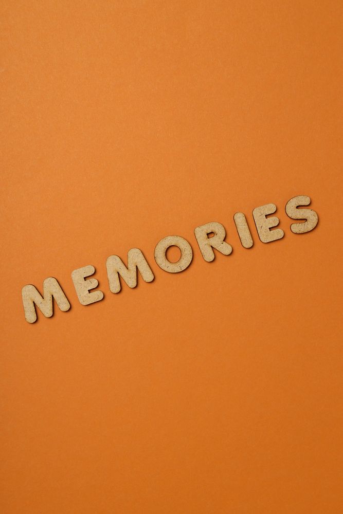 The word “Memories” written in cork in center of dusty orange background, vertical with copy space