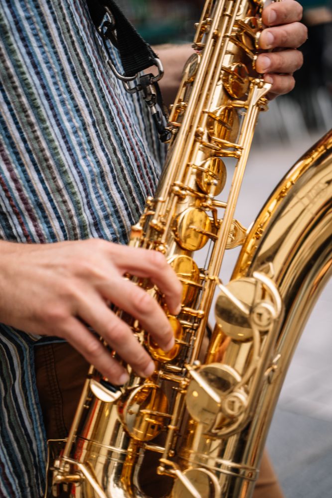 Crop view of male saxophonist playing sax in the street