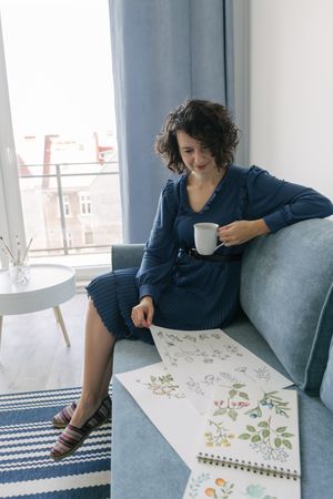 Young brunette woman with coffee looking album with pictures