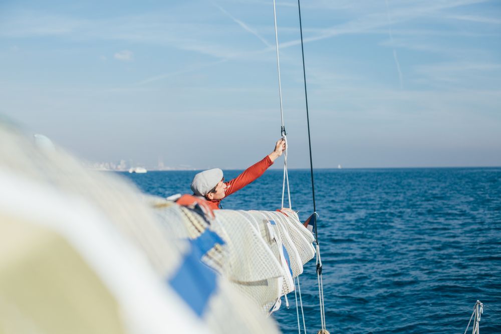 Man on sailboat arranging ropes