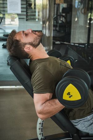 Strong man exercising with dumbbells in gym