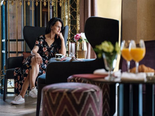 Pensive young female sitting in cozy armchair in cafe