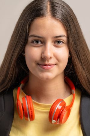 Close-up portrait of a happy young student with red headphones around her neck.