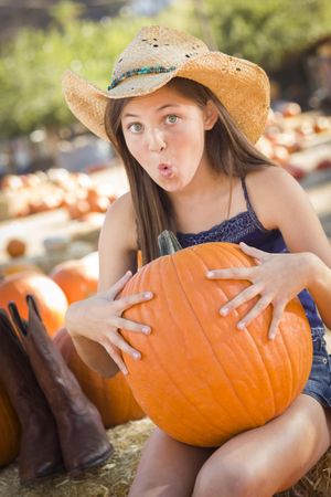 Preteen Holding A Large Pumpkin at the Pumpkin Patch.