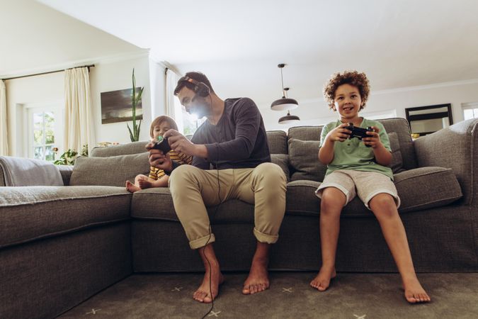 Happy man having fun with his kids playing video game at home