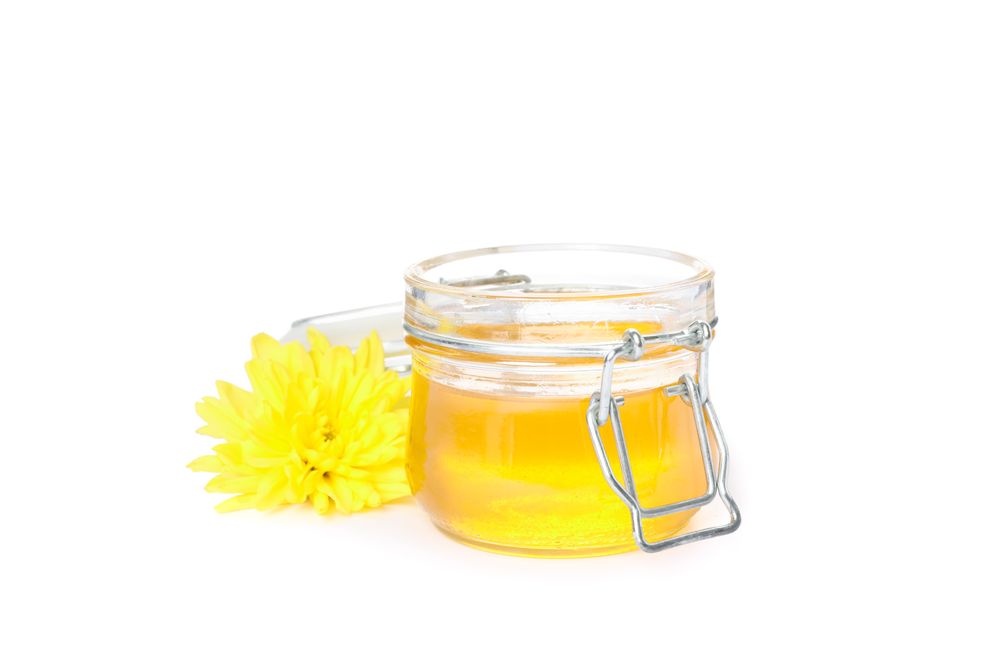 Chrysanthemum and glass jar with honey isolated on studio background