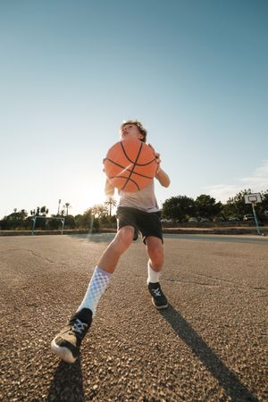 Active boy throwing ball in hoop during training