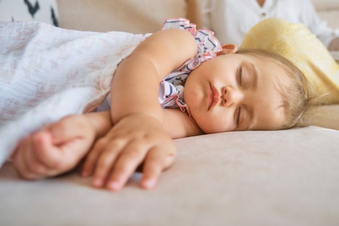 Toddler covered with blanket sleeping on sofa