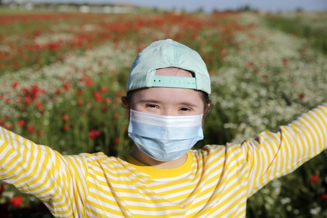 Excited child with arms open and wearing a medical mask