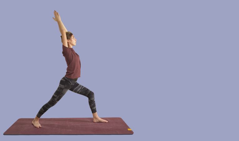 Woman practicing yoga warrior pose on mat