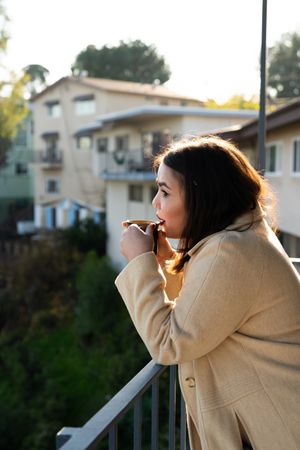 Young woman sipping coffee on patio looking out to view