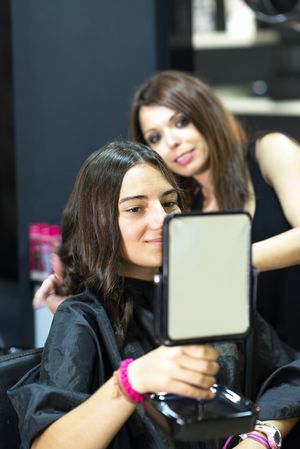 Hair stylist showing client new cut with mirror
