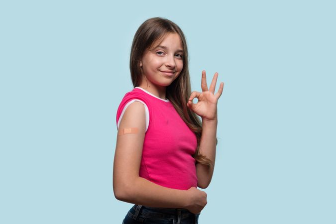 Girl with OK hand gesture after receiving vaccination