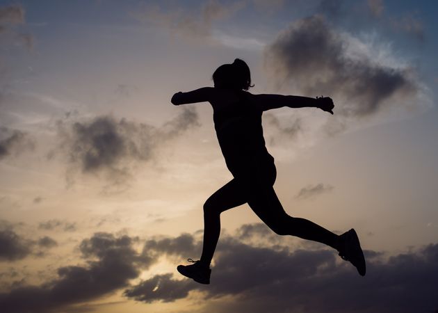 Jumping woman and sky with clouds at sunset