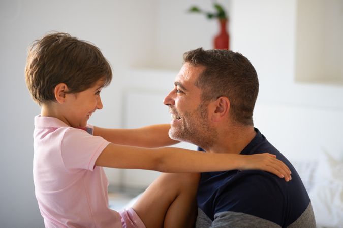 Child and dad smiling at each other at home