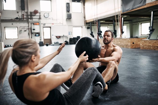 Man and woman working out with medicine ball on gym floor