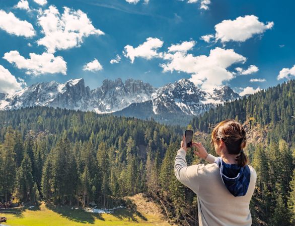 Woman in down vest taking photo of amazing landscape