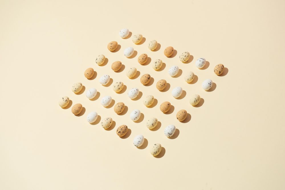 Speckled eggs  in rows on pastel yellow background