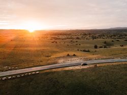 Bright sun setting over beautiful meadow and countryside road