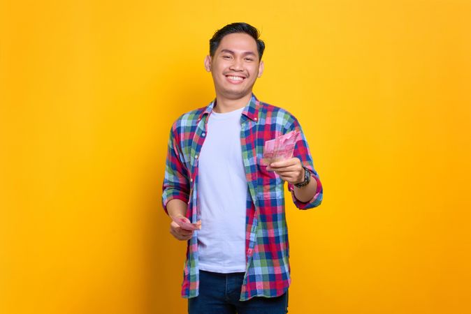 Asian man with a big smile holding money in studio shoot