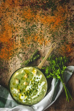 Green vegetable cream soup with crackers and peas in a pan