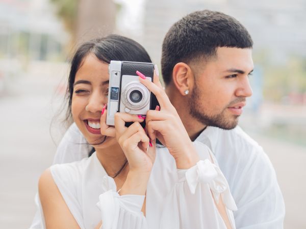 Woman taking photo and sitting with man on bench