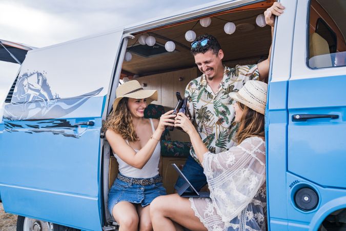Smiling friends clinking bottles of beer celebrating vacation