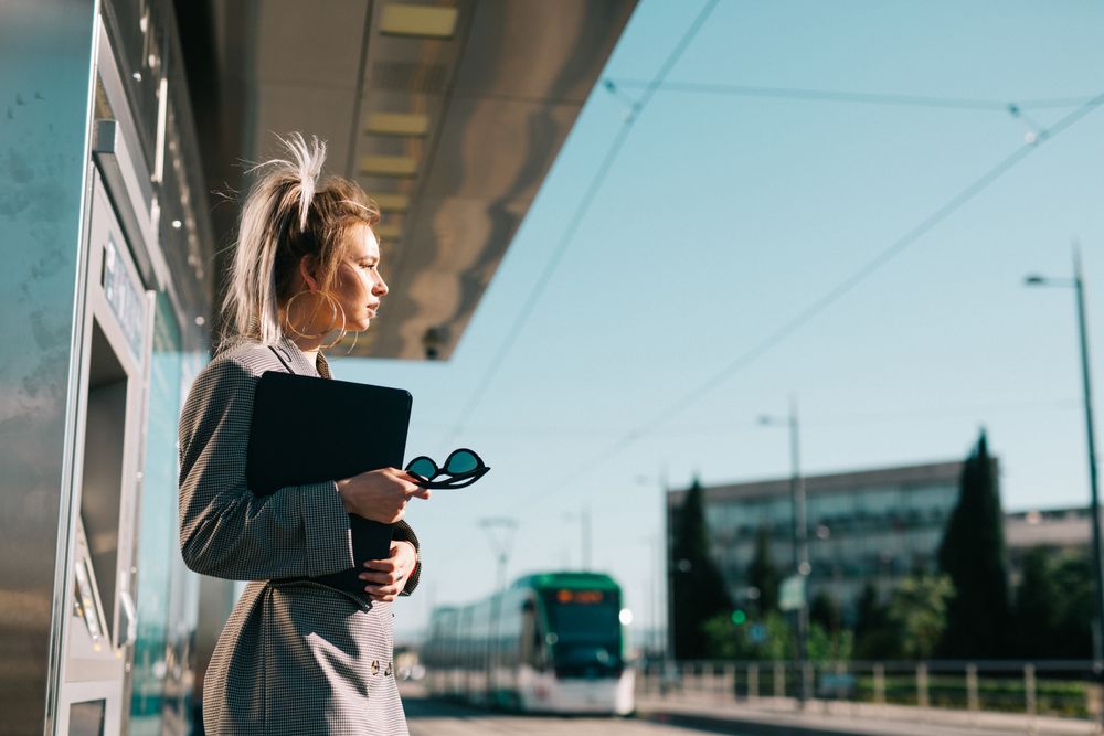 Thoughtful woman with ponytail hair holding tablet and waiting train