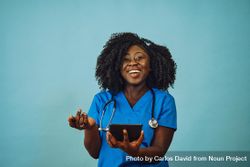 Portrait of happy Black medical professional dressed in scrubs with tablet 43PMrb