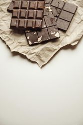Top view of stack of three chocolate bars on paper with copy space