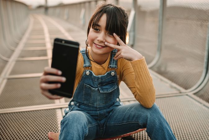 Funny girl taking selfie on smartphone on walkway